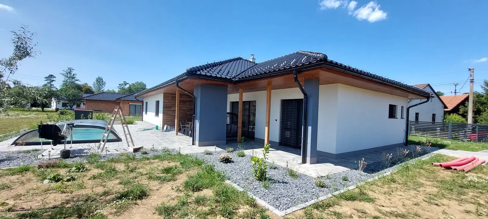 Novostavba bungalovu s tmavou střešní krytinou a zahradou
