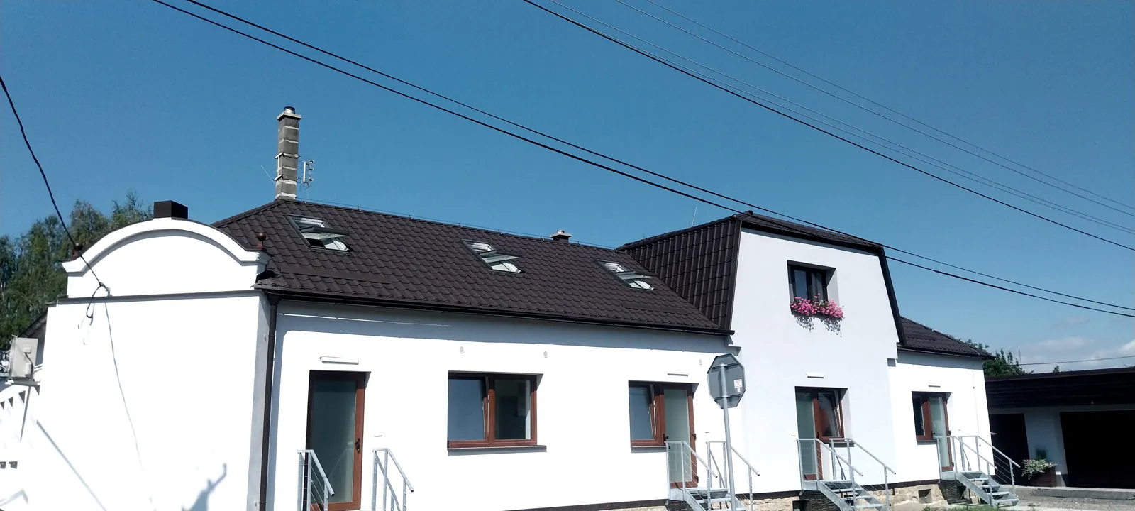 Dům po rekonstrukci střechy s novou hnědou krytinou a střešními okny