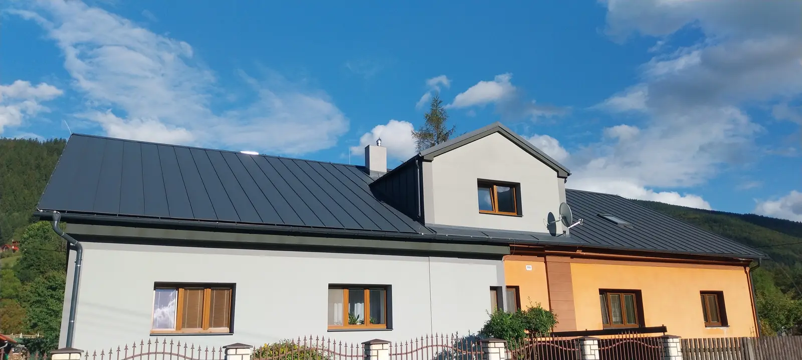 Rodinný dům s novou tmavou plechovou krytinou a vikýřem